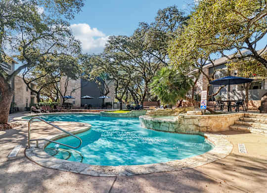 A swimming pool surrounded by trees and a patio area.