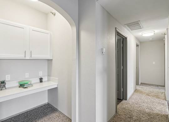 A hallway with a white cabinet and a grey carpet.