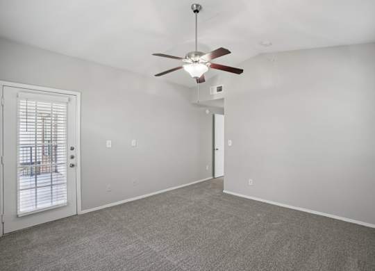 A room with a ceiling fan and carpeted floor.