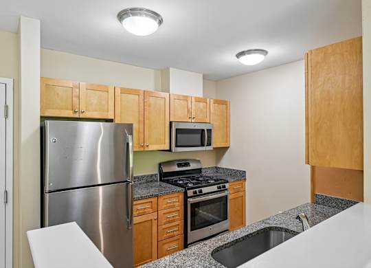A kitchen with a stainless steel refrigerator, microwave, oven, and sink.