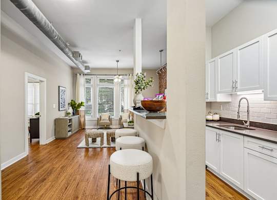 A kitchen with white cabinets and a wooden floor.