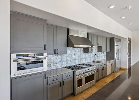 A modern kitchen with dark grey cabinets and stainless steel appliances.