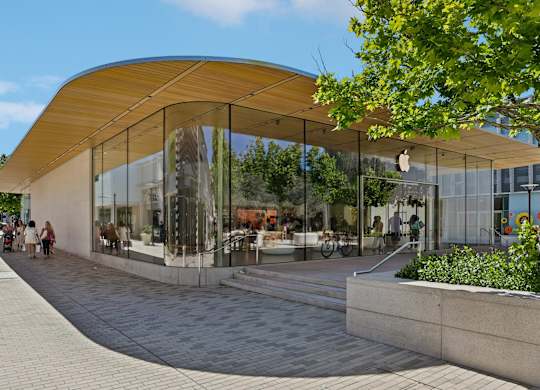 A modern building with a curved glass facade and a wooden roof.