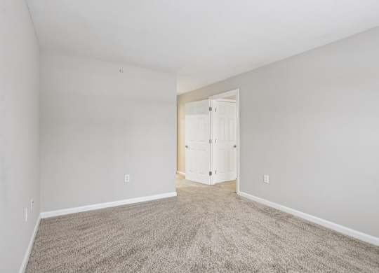 A room with a carpeted floor and a white door.