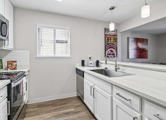 A kitchen with white cabinets and a wooden floor.
