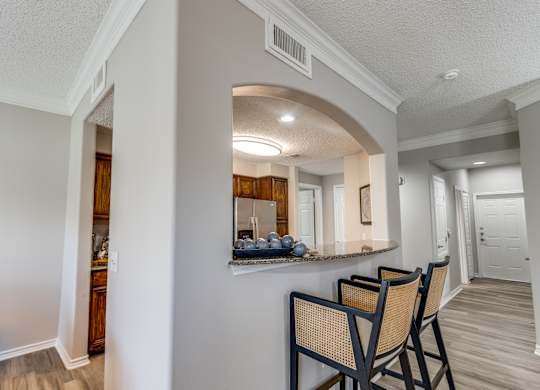 A kitchen area with a bar and chairs.