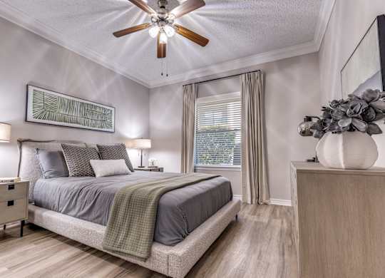 A bedroom with a bed, nightstand, and a ceiling fan.