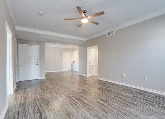 an empty living room with a ceiling fan