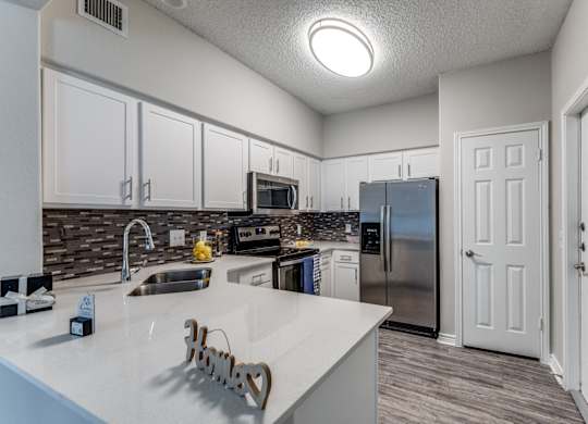 redesigned kitchen with white cabinets and stainless steel appliances at the preserve at great neck apartments