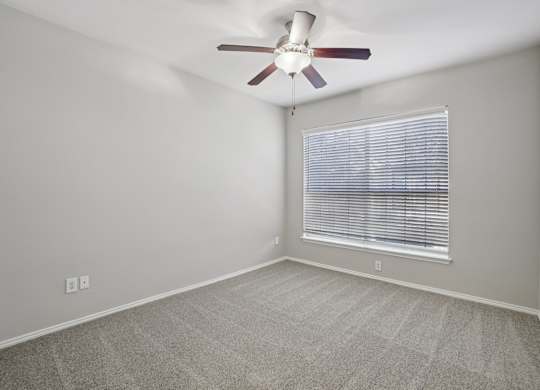 A room with a ceiling fan and a window with blinds.