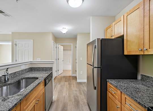 A kitchen with a black fridge and wooden cabinets.