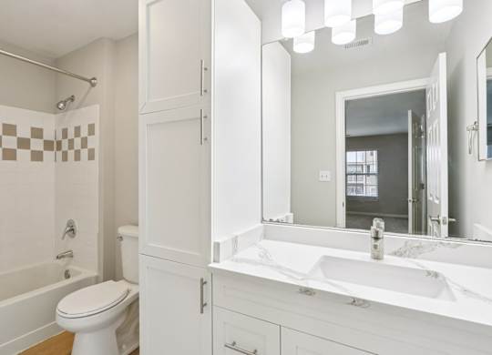 A white bathroom with a toilet, sink, and shower.