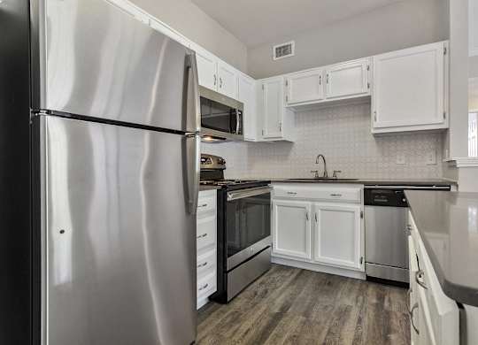 Apartments for Rent in Plano, TX - Carrington Park Kitchen with Stainless Steel Appliances, White Cabinets, and White Tile Backsplash