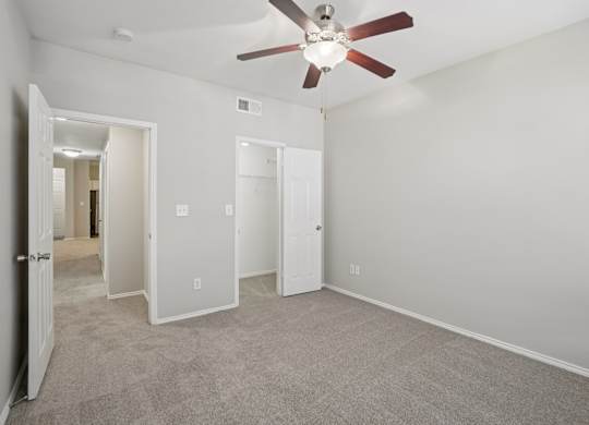 A room with a ceiling fan and carpeted floor.