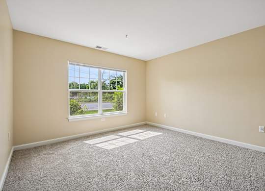 A room with a large window and carpeted floor.