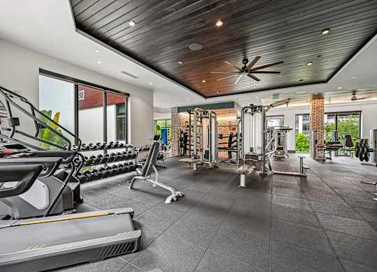 A gym with treadmills, weights, and a ceiling fan.