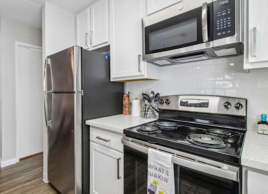 A kitchen with a stainless steel refrigerator, a white oven, and a white microwave above the stove.