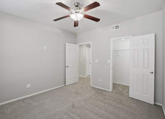 A room with a ceiling fan and three doors.