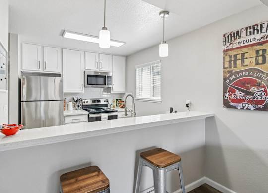 A kitchen with white cabinets and a fridge.