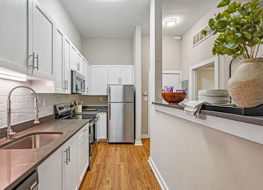 A kitchen with white cabinets and a stainless steel refrigerator.