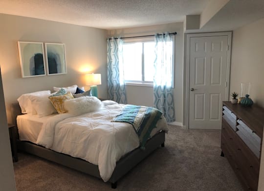 A bedroom with a bed, dresser, and window.