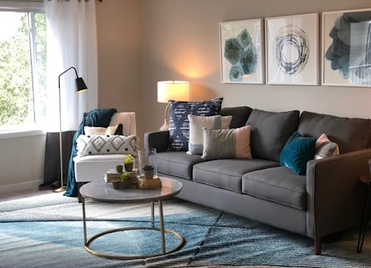 A grey couch with a white coffee table in front of it.