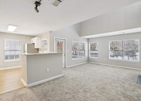 A spacious living room with a kitchenette and a large window.