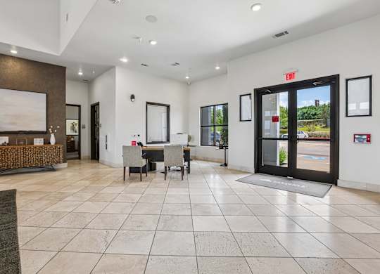 A spacious lobby with a reception desk and a view of the outdoors through a glass door.