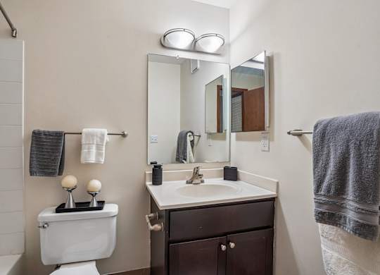 A bathroom with a toilet, sink, mirror, and towel.
