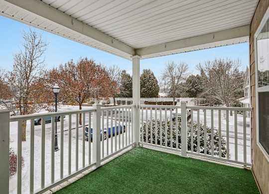 A white fence encloses a covered patio with a green carpet.
