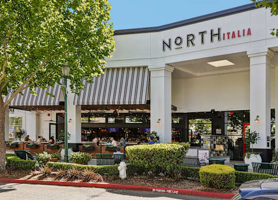 A North Italia restaurant with a striped awning and outdoor seating.