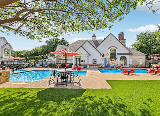 A large house with a pool and lawn chairs.