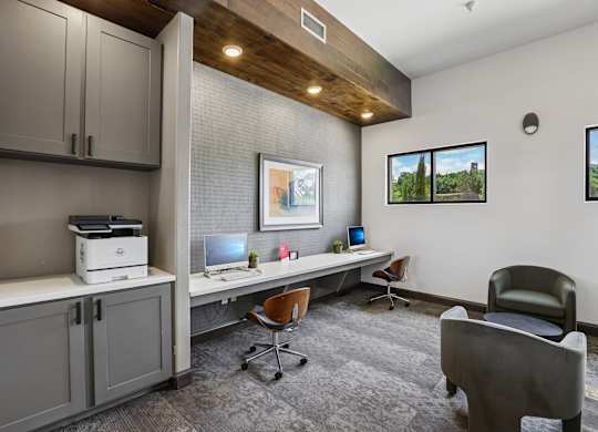 A room with a desk, chairs, and a printer.