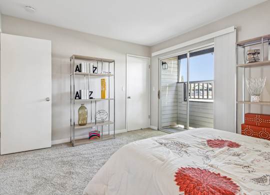 A bedroom with a bed, a shelf with letters, and a balcony.