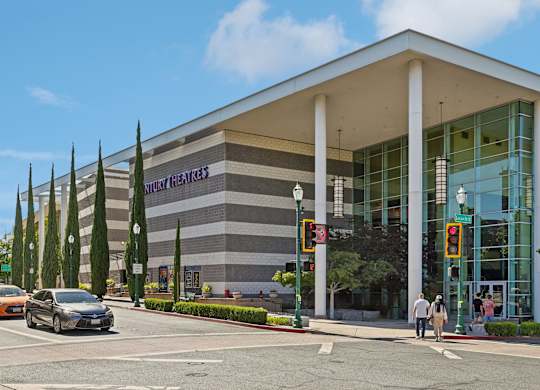 A car is driving on the road in front of a building with a sign that says