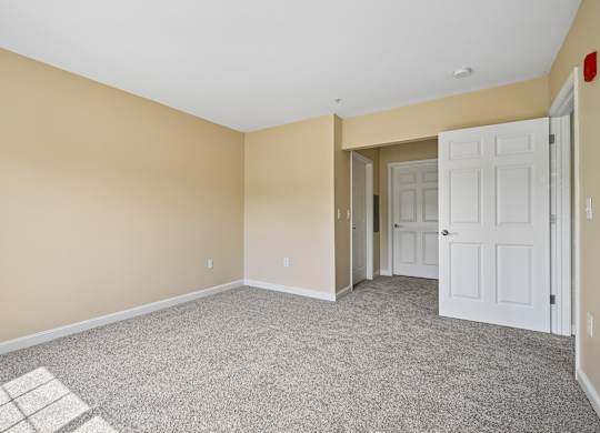A room with a carpeted floor and a white door.