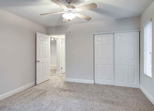 Apartments in Roswell, GA for rent - 2200 Big Creek Apartments - Bedroom with plush carpeting, ceiling fan, and storage space in closet