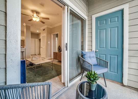 a porch with a blue door and a chair and a table