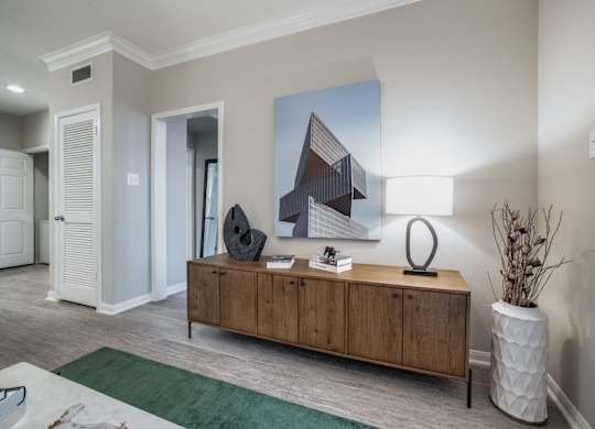 an open living room with a wooden dresser and a table with a lamp
