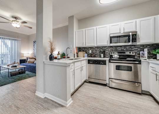 spacious kitchen with stainless steel appliances and white cabinets in an apartment