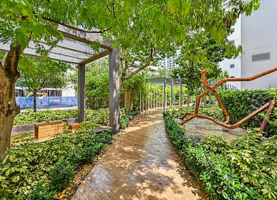 A walkway in a park with a bench and a sculpture.