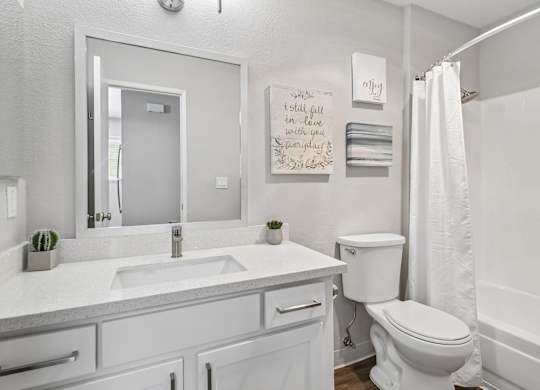 A white bathroom with a toilet, sink, and mirror.