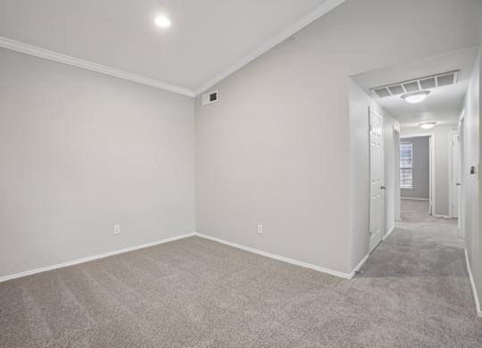 A spacious room with carpeted floor and white walls.