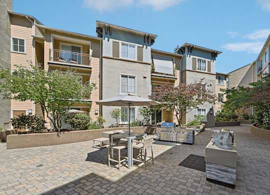 A patio with a table and chairs is surrounded by apartment buildings.