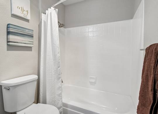 A white toilet sits next to a white bathtub in a bathroom.