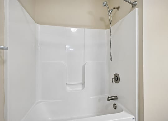 A white bathtub with a shower head and faucet.