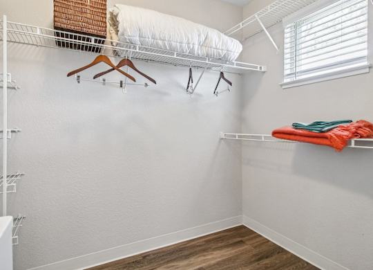 A white closet with a white ironing board and clothes hanging on it.