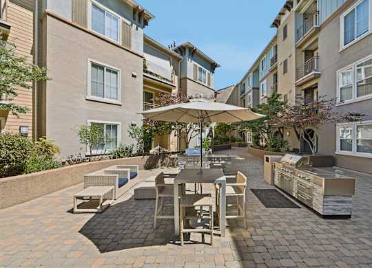 A patio with a table and chairs is surrounded by apartment buildings.