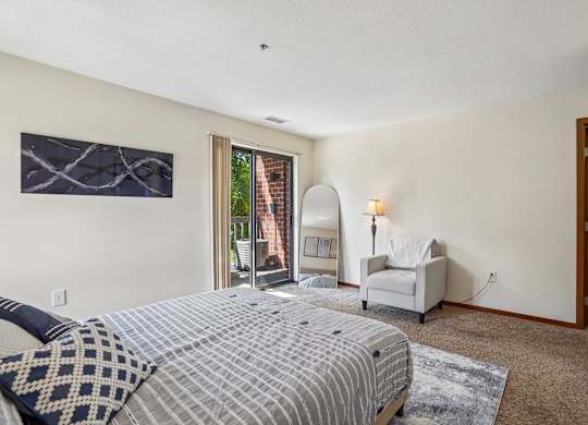 A bedroom with a large bed and a chair.