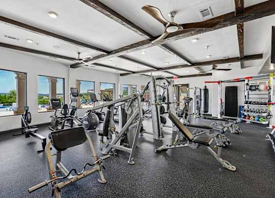 A spacious gym with a variety of equipment and a view of the outdoors through large windows.